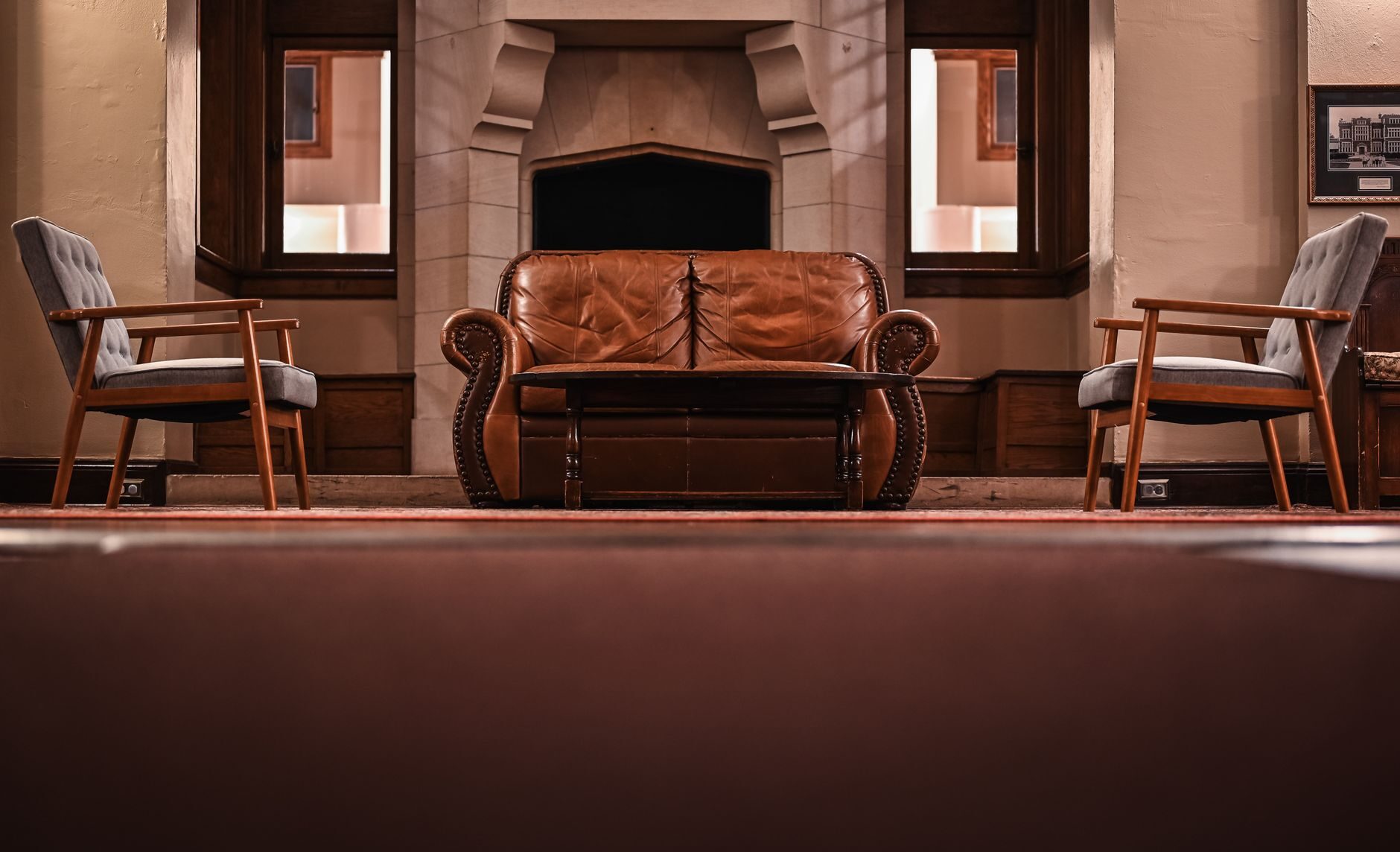 Brown leather loveseat in a stone fireplace alcove lit by warm amber light